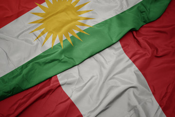 waving colorful flag of peru and national flag of kurdistan.