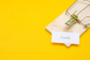 mousetrap with a piece of paper and the inscription Credit on a yellow background with copy space. The concept of debt, according to