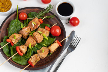 Chicken breast skewers with bell pepper. The meat is marinated in soy sauce with honey and mustard. Decorated with sprigs of rosemary. In the background are soy and vegetables for the salad.