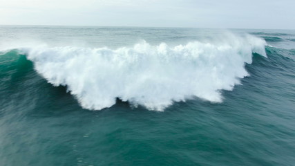 A spectacular flight over a giant ocean wave. A large wave collapses and foams.