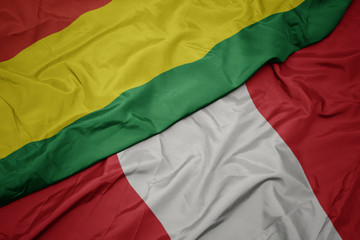 waving colorful flag of peru and national flag of bolivia.
