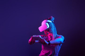 Woman is using virtual reality headset. Neon light studio portrait.