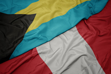 waving colorful flag of peru and national flag of bahamas.
