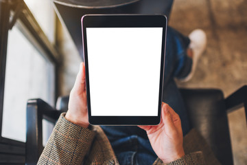 Top view mockup image of a woman sitting and holding black tablet pc with blank white desktop screen