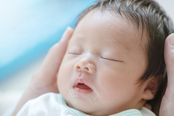 Closeup a baby sleeping comfortably in the mother's arms