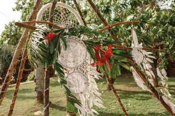 big white Dreamcatcher connected by a hook hanging on a tree in beams of the sunset sun, white candles of the different sizes. knitting, handmade, wedding, decor - concept