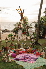 Wooden wigwam decorated with green  branches in the backyard, event or wedding in boho style. beautiful original triangular wooden wedding arch with flowers and greenery in the open air © Yevhenii