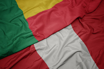 waving colorful flag of peru and national flag of benin.
