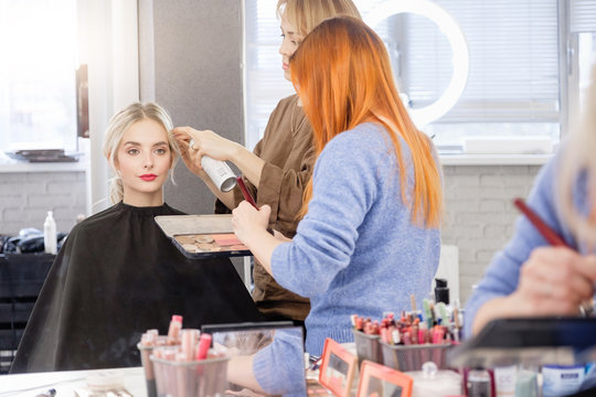 Young female madel visits professional stylist, makes creative hairstyle and makeup for important social event. Young woman in makeup artist chair. Client of fashionable salon, luxury beauty studio