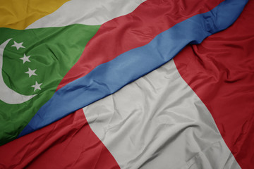 waving colorful flag of peru and national flag of comoros.