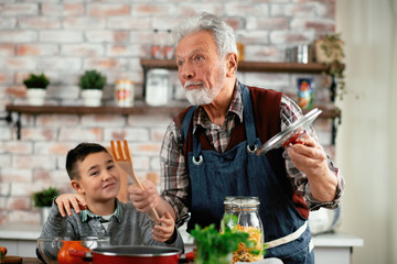 Grandpa and grandson in kitchen. Grandfather and his grandchild having fun while cooking.