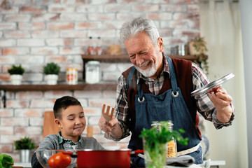 Grandpa and grandson in kitchen. Grandfather and his grandchild having fun while cooking.
