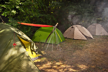 Camping tent. Orange hammock stretched between tents. Smoke campfire over tents.
