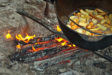 Fototapeta na wymiar Potatoes are cooked in a large pot on fire. Food is cooked on a campfire in marching conditions.