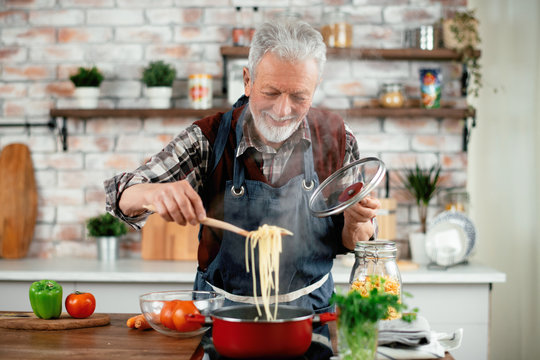 Man in kitchen. Old man cooking pasta. 