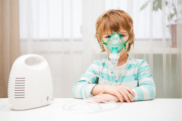Little boy making inhalation with nebulizer at home. 