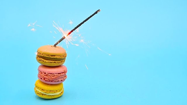 Stack of delicious macaron with burning sparkle on blue pastel background. Celebrating concept .