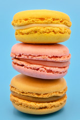 Stack of sweet french macaroons with vintage pastel colored tone on blue background .