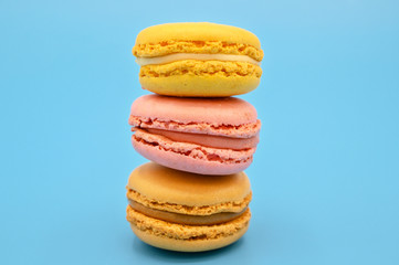 Stack of sweet french macaroons with vintage pastel colored tone on blue background .