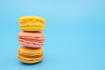 Stack of sweet french macaroons with vintage pastel colored tone on blue background .