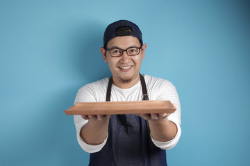 Asian Male Chef or Waiter Shows Empty Wooden Plate, Presenting Something, Copy Space