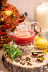 Hot fruit red berry tea with steam in the teapot, a cup of tea, with mint, berries, lemon slices on on wooden background. Food and drink, still life health care.