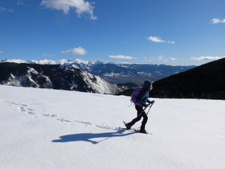 Naklejka na ściany i meble Jeune femme randonneuse en raquette dans la neige en montagne sous le soleil des Pyrénées Orientales de Cerdagne