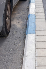 White and blue coloring of the curb on the road to indicate paid Parking in Israel