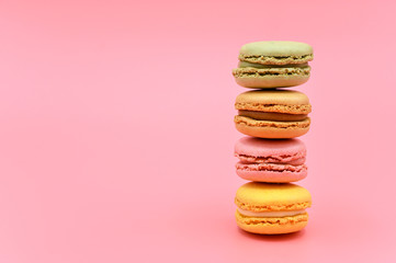 Stack of sweet french macaroons with vintage pastel colored tone on pink background .