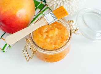 Homemade mango facial mask (exfoliating sugar scrub) in the glass jar. Fruit DIY beauty treatment...