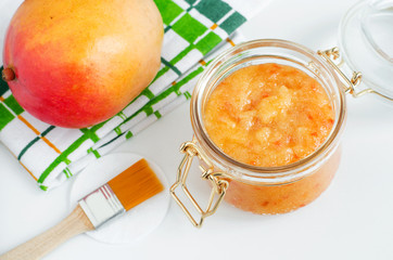 Homemade mango facial mask (exfoliating sugar scrub) in the glass jar. Fruit DIY beauty treatment and spa recipe. Copy space