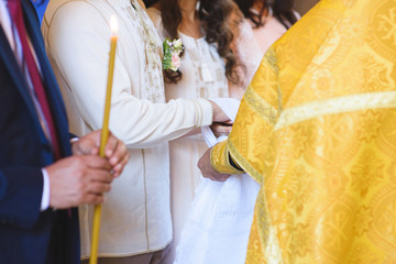 priest tying knot around newlyweds hands