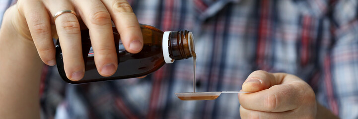 Sick man holding in hands vial with syrup close-up