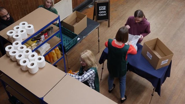 Man donating food to a foodbank. Volunteers work hard in the background to sort out the food donations. Aerial View. Looking down from above