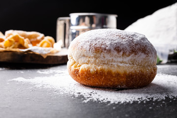 Donut covered with powdered sugar on the stony worktop.