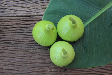 Lagenaria siceraria on banana leaf on brown wooden table.