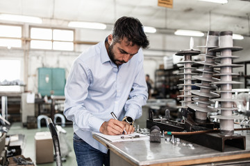 Middle age businessman doing quality control checking at industry production. Factory for...