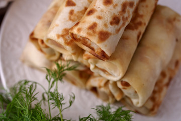 Russian pancakes with filling, lying on a plate with a slide