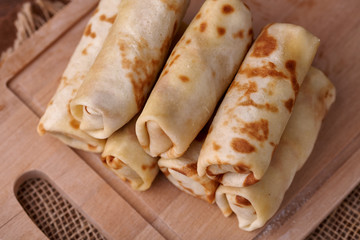 Russian pancakes with filling, lying on a wooden board with a slide