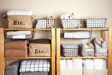 Bed sheets, duvet covers and towels are folded vertically. Metal and fabric black baskets. The...