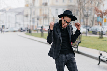 Cheerful young african man happy posing in park in morning. Outdoor portrait of slim stylish guy in...
