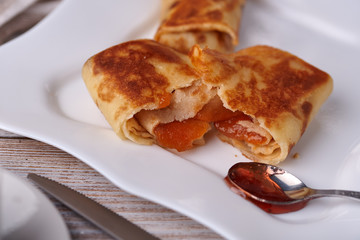 Russian pancakes with filling, lying on a plate with a slide