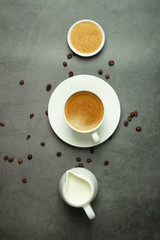 cup of black coffee, milk jug and coffee beans on a black background