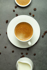 cup of black coffee, milk jug with milk and coffee beans on a black background