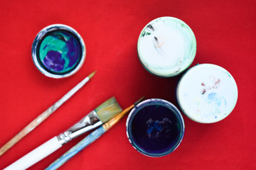 jars with gouache and brushes on a red background
