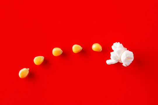Corn grains transforming into a popcorn on red background