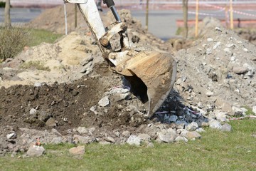 Obraz premium A mini excavator digs a ditch for laying pipes.