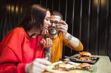 Young couple enjoying the tasty fast food in restaurant