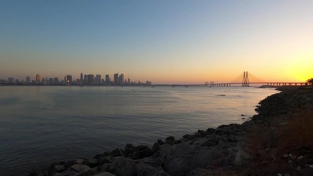 Real time Wide angle footage of beautiful city skyline and bandra worli sea link bridge by the sea during sunset as seen from Bandra Reclamation, Mumbai, India. GP0190.