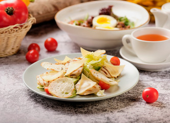 Restaurant cold caesar salad with chicken, cherry tomato, green leaves and herbs on a stone background. Food and drink concept.